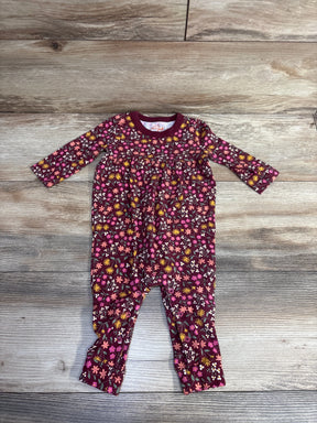 Baby romper with long sleeves, floral print in pink, yellow, white on wood floor
