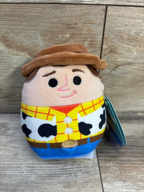 Front view of 5-inch Woody Squishmallows plush showing brown hat, yellow plaid shirt and cow-print vest on wood background