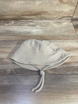 Top down view of baby waffle knit bucket hat beige showing textured waffle fabric and knotted chin ties on wood background