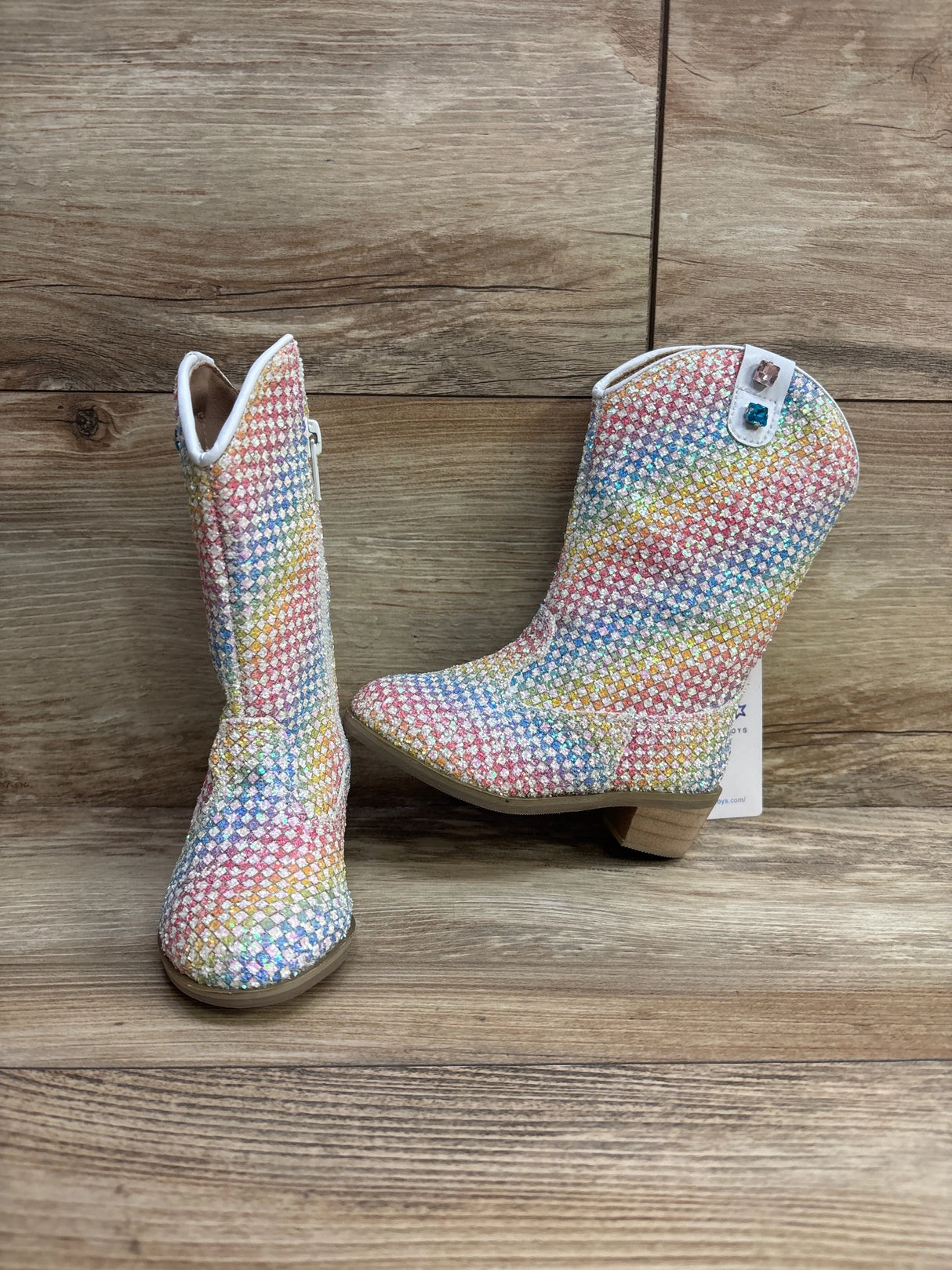 Children's rainbow glitter cowboy boots with colorful checkered pattern on wooden floor