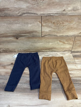 Front view of two Carter's ribbed baby pants navy and brown with elastic waistbands and cuffed ankles on wood background