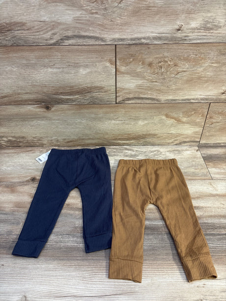 Front view of two Carter's ribbed baby pants navy and brown with elastic waistbands and cuffed ankles on wood background