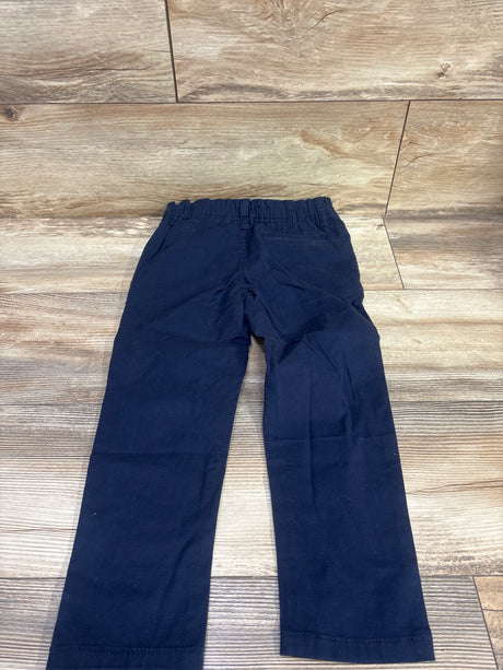 Front view of Oshkosh navy chino pants in size 5T showcasing elastic waistband and pockets on a wood floor