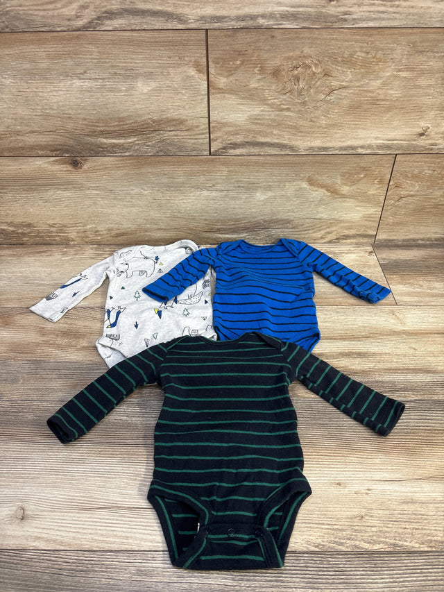 Top view of three Carter's long-sleeve 3M bodysuits showing green-striped, blue-striped, and gray animal-print designs on wood background