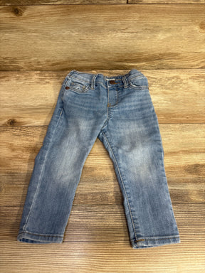 Light blue toddler jeans on wooden floor, featuring pockets and button closure, kids clothing