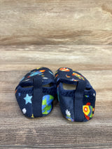 Rear view of Soft Cozy Space baby slippers showing navy space-print rockets, planets and stars with heel pull tabs on wooden surface