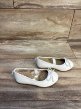 Side view of Cat and Jack Nora slip-on white toddler ballet flats size 7C showcasing elastic strap and bow detail on wood floor background