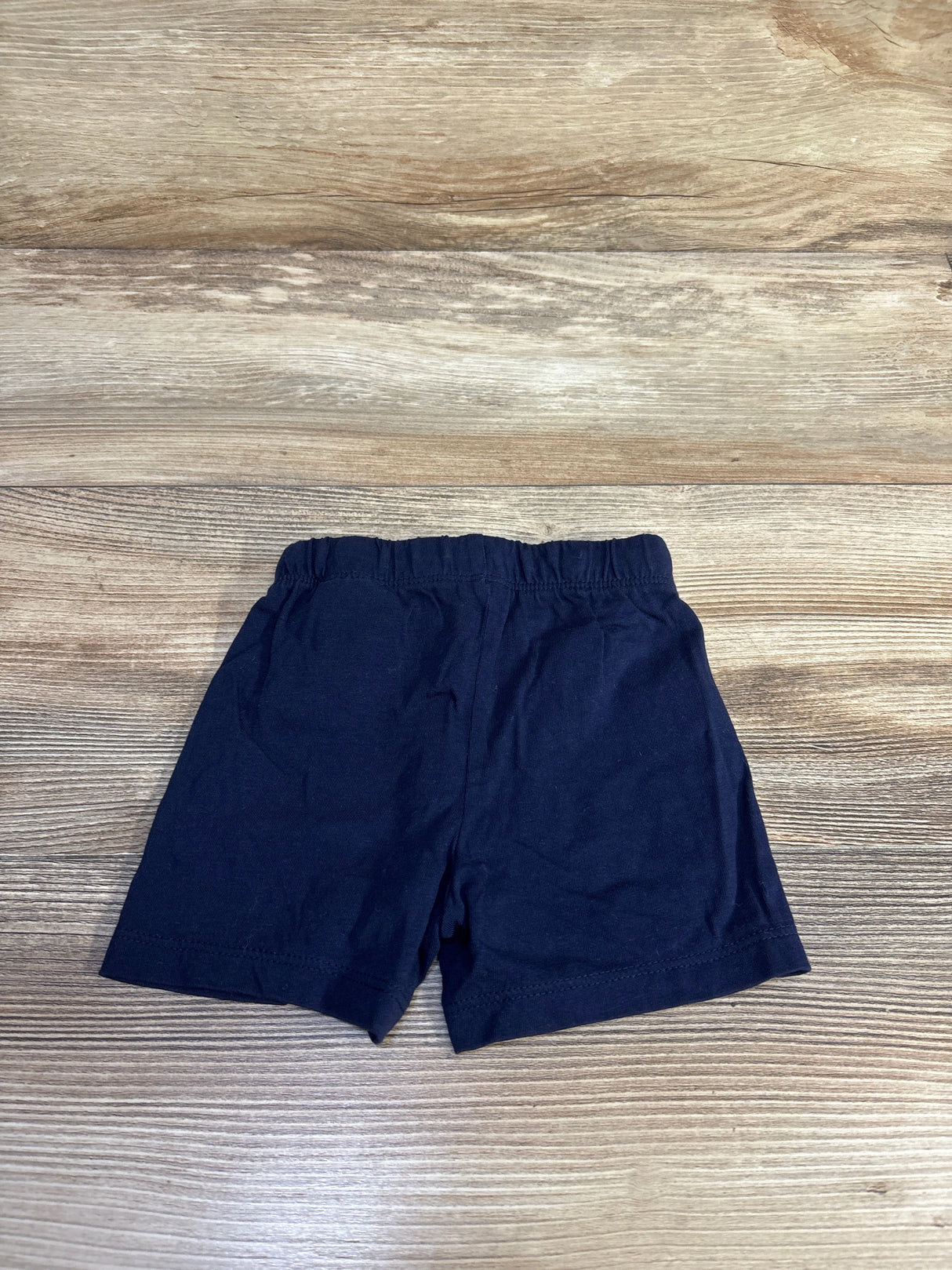 Flat lay of navy H&M baby pull on drawstring shorts size 6 months showing elastic waistband on wood background