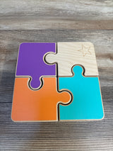 Colorful wooden four-piece puzzle for kids on a wood surface, featuring a star engraving