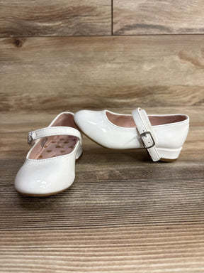 White toddler Mary Jane dress shoes with buckle straps on a wooden floor