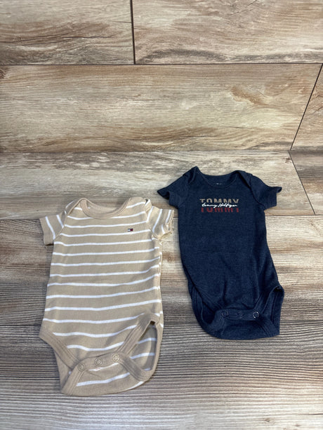 Two baby bodysuits, one beige striped and one navy graphic, displayed on wood background