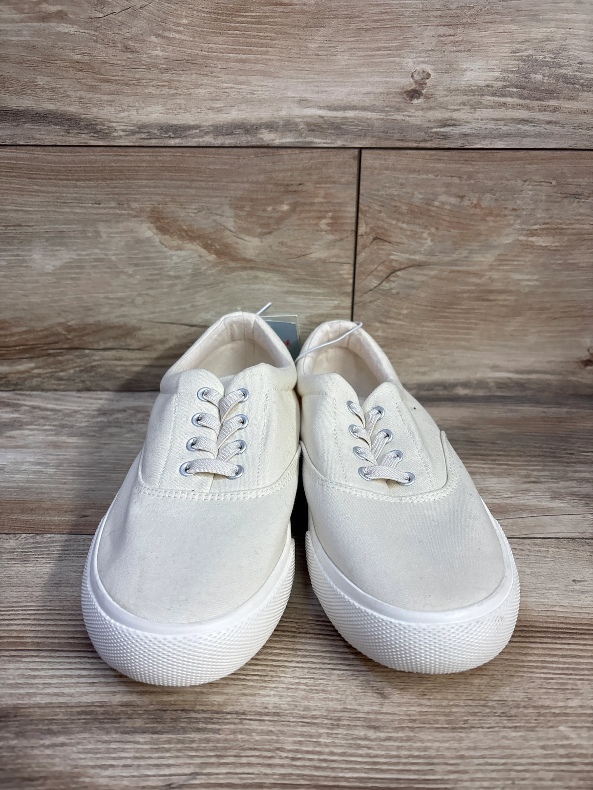 Front view of Cat & Jack Tyler slip-on sneakers in off-white with canvas upper, white rubber sole on wood background