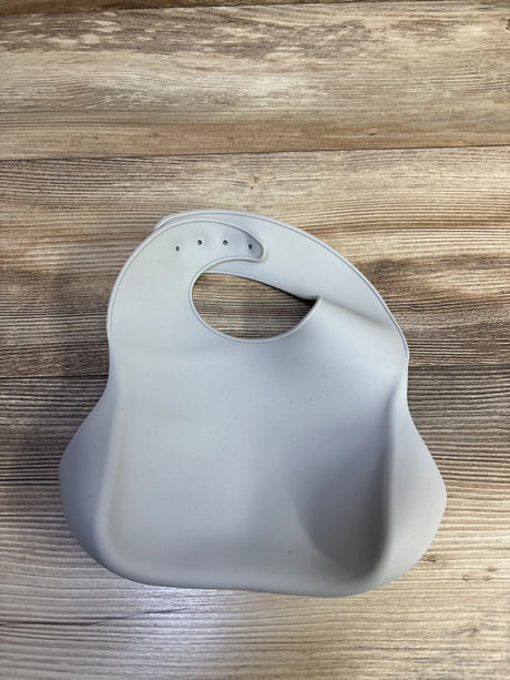 Front view of grey O’doe silicone bib showcasing raised crumb-catching pocket on a wood-grain background