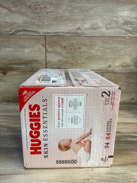 Huggies Skin Essentials size 2 diapers box for babies, 74 count, on wooden floor.