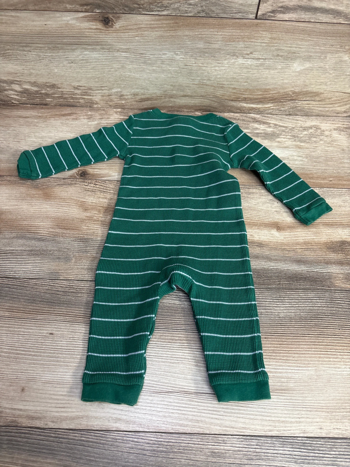 Green and white striped long-sleeve baby romper on wooden floor, kids clothing