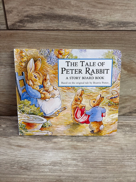 Front cover of The Tale of Peter Rabbit story board book showing illustrated rabbits in a garden scene on a wood surface