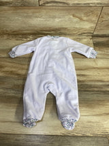 White baby sleeper with floral trim on sleeves, collar, and feet laid on wooden floor