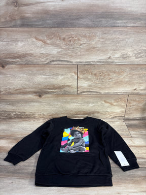 Black kids sweatshirt featuring a colorful graphic of a baby with a crown, laid on wooden floor