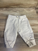 Top-down view of H&M baby cream drawstring joggers showing elastic waistband with tied drawstring and ribbed cuffs on a wood background