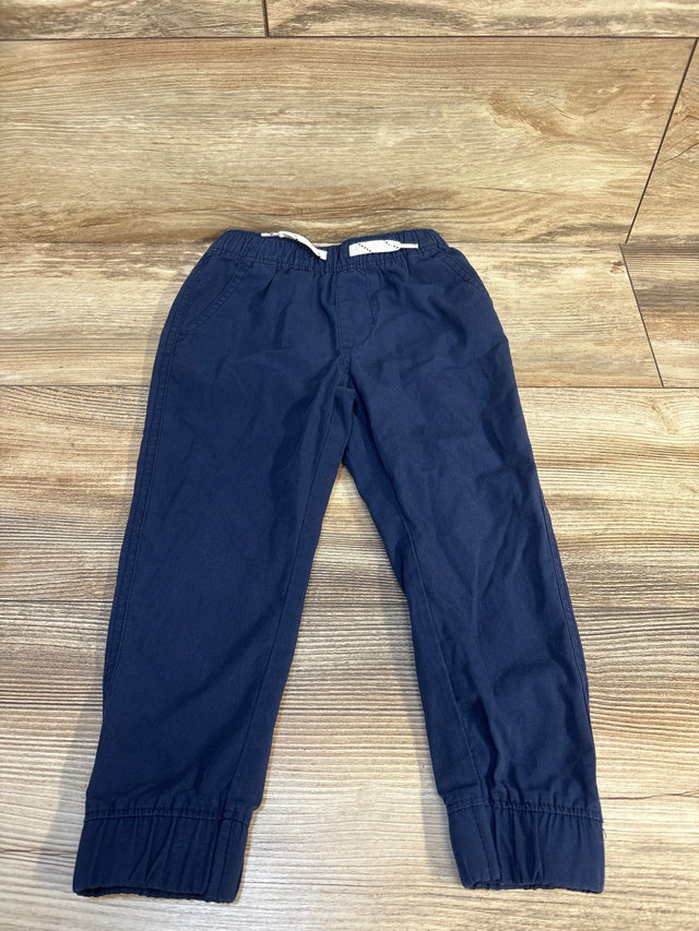 Navy blue kids jogger pants with elastic waist and cuffs, laid flat on wood floor