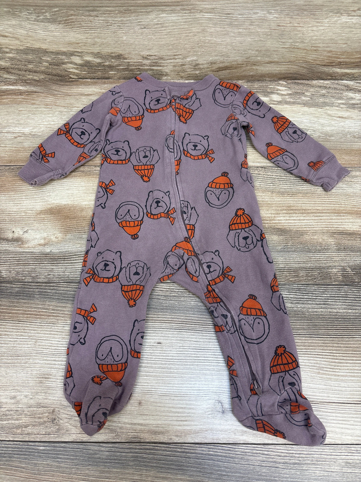 Top view of Carter’s mauve 9-month footed sleeper with long sleeves, front zipper, and winter animal print on a wood-grain background