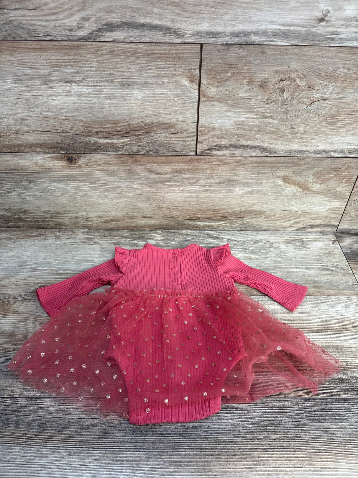 Pink infant tutu bodysuit with gold polka dots on wooden background