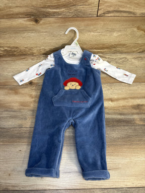 Front view of baby overalls and shirt set showcasing blue velour overalls with Paddington bear motif over white long sleeve on hanger on wood