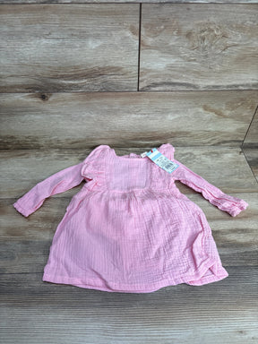 Pink long sleeve baby dress with ruffle shoulders on wood background, gently used kids clothing