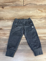 Gray kids jogger pants with zip pockets and logo, laid flat on wood background