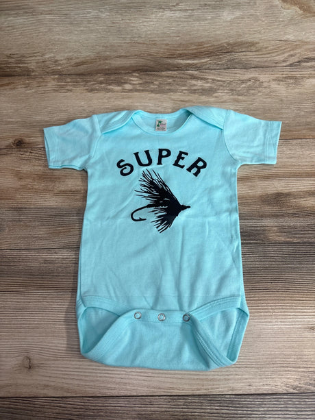 Flat-lay of blue Laughing Giraffe Super Fly bodysuit 12-18 months showing black SUPER text and fishing-fly graphic on wood