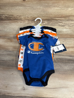 Set of Champion brand baby bodysuits in blue, white, black, and orange on wooden surface