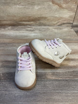 Light pink toddler shoes with heart cutout details and rubber soles on wood background