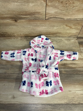 Plush baby bathrobe with pink and navy bow print and hood on wood floor