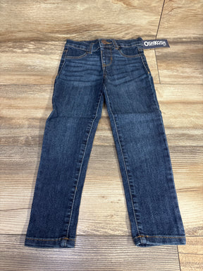 OshKosh blue denim jeans for kids laid flat on wood floor