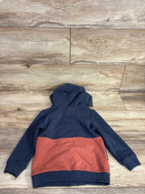 Two-tone kids zip hoodie with navy top and rust bottom, laid flat on wood floor
