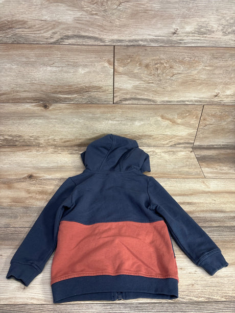 Two-tone kids zip hoodie with navy top and rust bottom, laid flat on wood floor