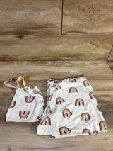 Folded white Kyte Baby nursing and car seat cover with brown and rust rainbow print and matching drawstring pouch on wood background