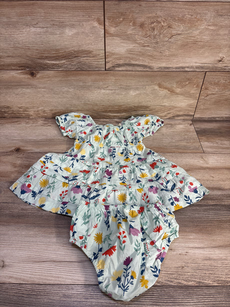 Flat lay of green floral cotton tiered dress with matching bloomers, puffed sleeves and tiered skirt on wood background
