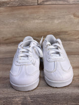 Pair of white toddler sneakers with laces on wooden background