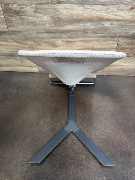 Top-down view of Baby Delight Alpine Deluxe bouncer showing pink mesh seat and dark gray Y-shaped metal base on wood-look floor