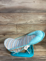 Side view of Summer Infant Foldaway baby bather showing turquoise base, padded head support, patterned seat on wood background