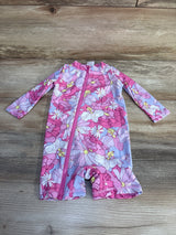 Flat lay of newborn pink floral rashguard romper showcasing front zipper and long sleeves on wooden floor background