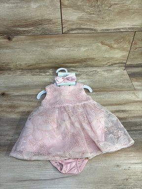 Front view of pink baby dress set with floral lace overlay, matching bloomer and bow on wood background