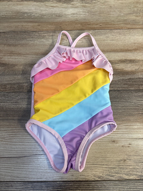 Girls' rainbow striped one-piece swimsuit with ruffle trim, laid flat on wooden background