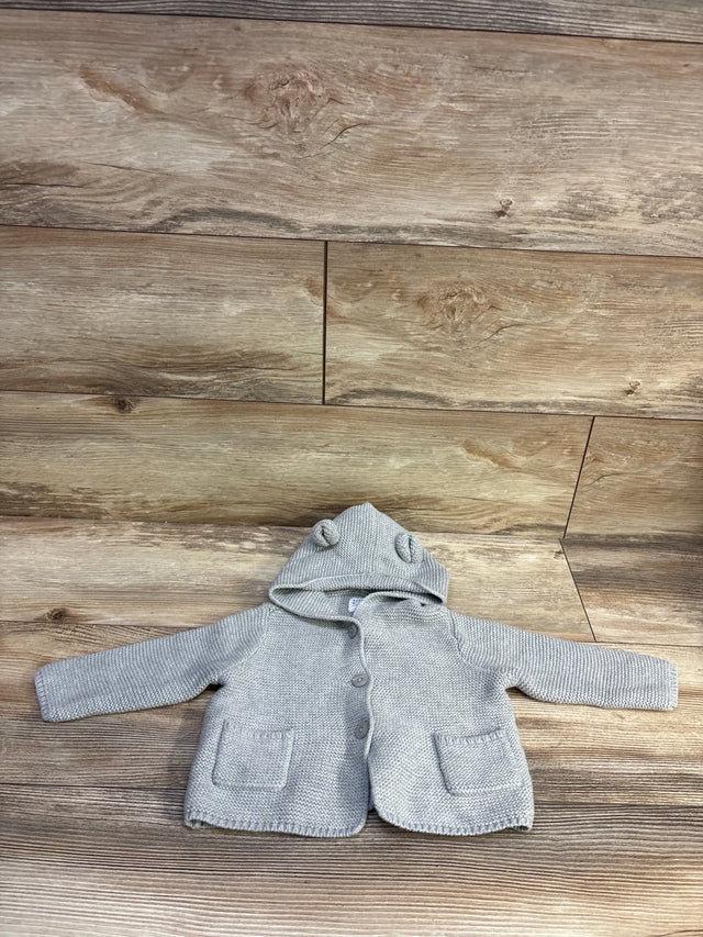 Grey Baby Gap knit hooded cardigan with bear ears and pockets on a wood background
