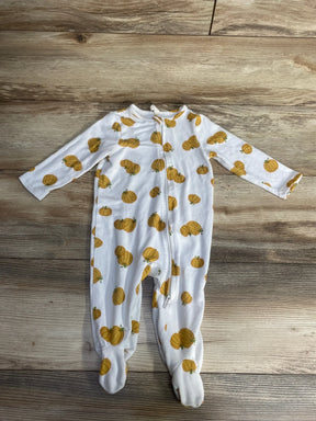 White baby footed pajamas with yellow pumpkin print, laid flat on wooden floor