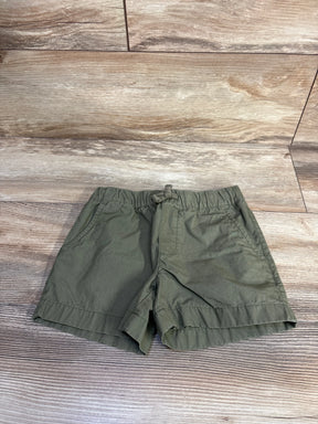 Flat lay of Carter's toddler drawstring shorts in olive green showing elastic waistband and front pockets on wood background