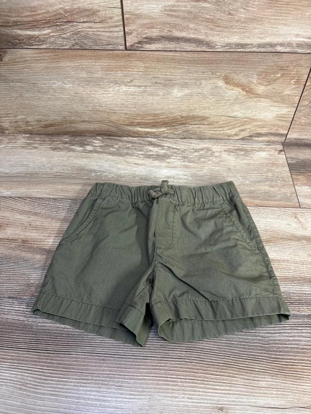 Flat lay of Carter's toddler drawstring shorts in olive green showing elastic waistband and front pockets on wood background