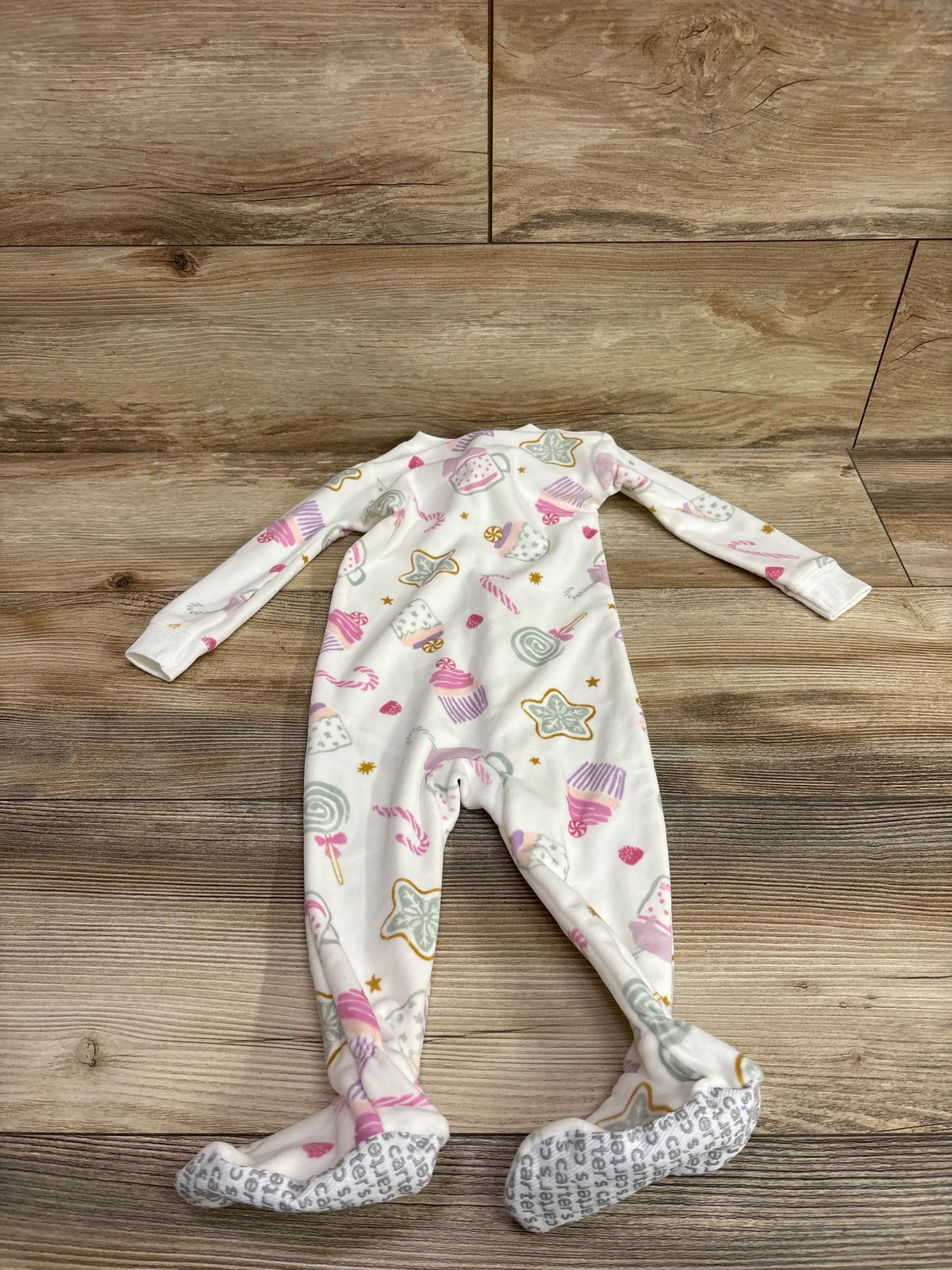 Front view of Just One You white blanket sleeper in size 12m showcasing candy pattern and footed design on wood floor