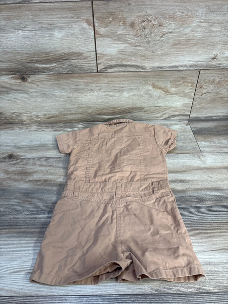Back view of tan toddler utility romper showing short sleeves, collar, stitched waist with belt loops on wood background